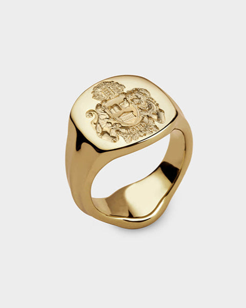 A yellow gold signet ring with a family crest seal engraving.